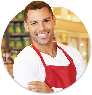 Male C-store worker smiling with arms crossed, wearing a red apron