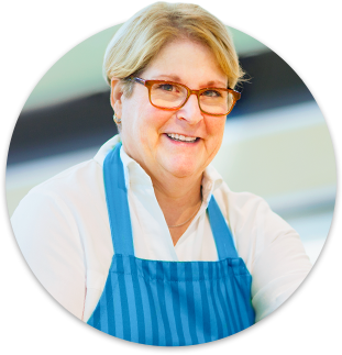 Blonde female supermarket worker wearing red glasses and a blue apron